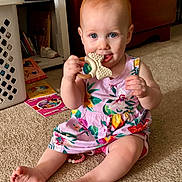 Sophia joined the competition — help win amazing prizes! baby, child, toddler, smiling, sitting, indoor, playroom, floral_dress, pink_clothing, teether, toy, bow_shaped_toy, baby_teething, blue_eyes, carpet, books, laundry_basket, furniture, portrait, happy