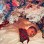 baby, celebration, christmas, christmas_tree, closeup, colorful_lights, cute, festive, holiday_decor, holiday_lights, indoors, infant, lying_down, mittens, peaceful, plaid_dress, presents, soft_texture, tree_skirt, white_tree