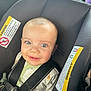 baby, blue_eyes, car_seat, child, child_safety, close_up, cute, face, giraffe_pattern, happy, infant, infant_clothing, onesie, person, safety_harness, seatbelt, smile, straps, transportation, warning_label