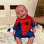 Riley joined the competition — help win amazing prizes! baby, child, smiling, spiderman_costume, red, blue, plastic_chair, blanket, hand, indoors, brick_wall, happy, cute, portrait, sitting, infant, person, clothing, foot, head