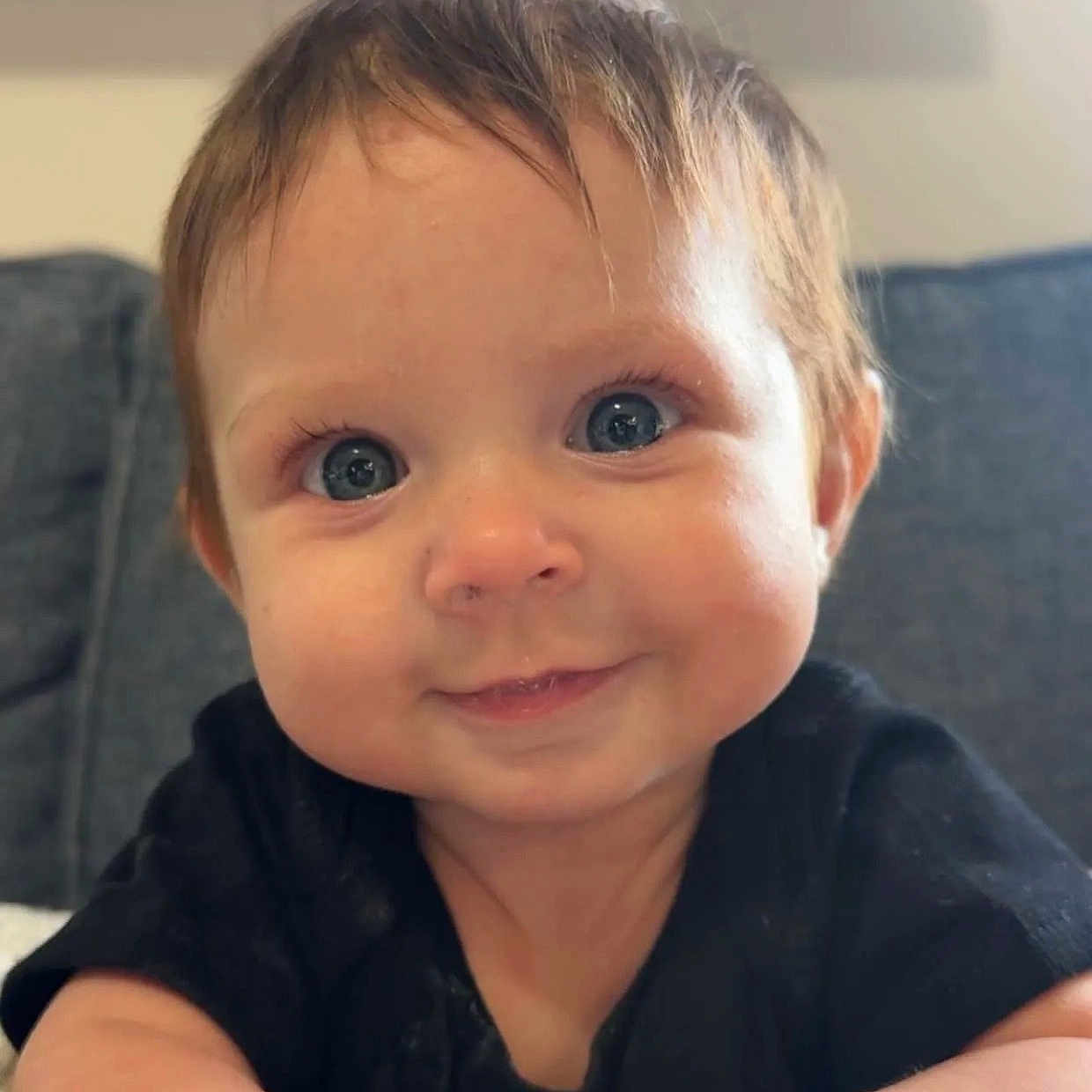 Everly Belle is registered to the contest to win money with this photo: baby, child, infant, smiling, face, hands, black_shirt, blue_eyes, cheeks, couch, indoor, portrait, closeup, cute, happy, young_child, person, skin, hair, sitting
