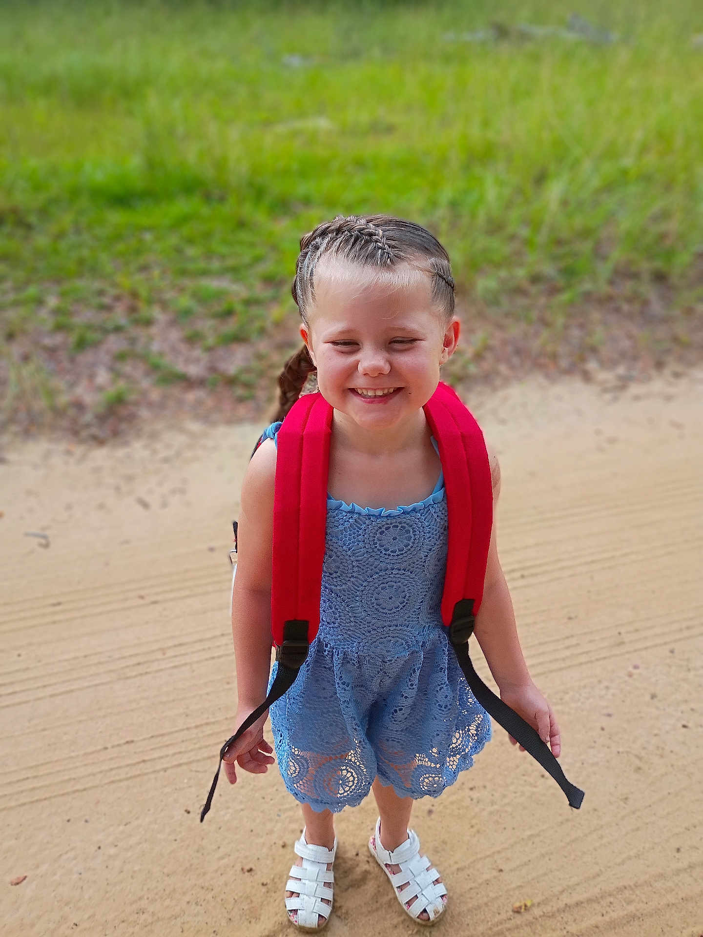 Aymiee joined the competition — help win amazing prizes! child, girl, smiling, braided_hair, red_backpack, blue_dress, lace, sandals, outdoor, grass, sandy_path, happy, standing, summer, daylight, cute, portrait, fashion, nature, feet