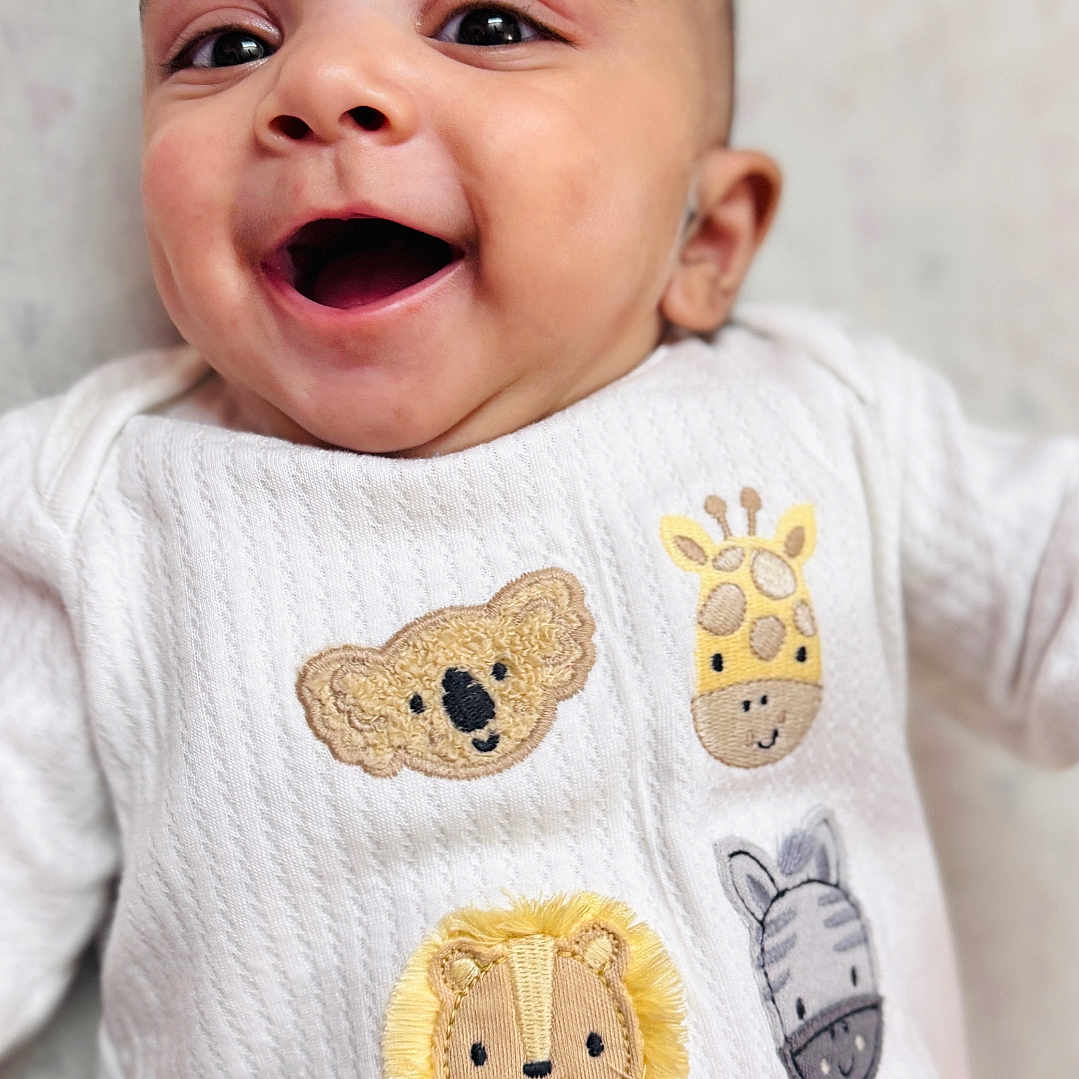 Hunaid is registered to the contest to win money with this photo: baby, child, closeup, cozy, cute, embroidered_animals, giraffe, happy, indoors, infant, koala, lion, lying_down, portrait, sleepy_friends, smiling, soft_texture, white_clothing, young_child, zebra