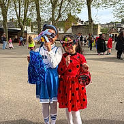 Shadya a rejoint le concours — aidez-le/la à gagner de superbes lots ! child, children, costume, mask, playground, outdoor, trees, people, group, festive, daylight, smile, fun, party, red_dress, blue_cheerleader, props, shoes, pavement, casual