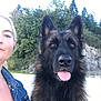 dog, german_shepherd, woman, portrait, outdoor, nature, trees, rocks, leash, pet, animal, canine, happy, tongue_out, fur, face, denim_jacket, casual, selfie, daylight