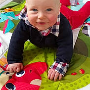 Ezekiel a rejoint le concours — aidez-le/la à gagner de superbes lots ! baby, child, smiling, crawling, play_mat, colorful, red_fox, navy_sweater, checkered_shirt, floor_tiles, indoor, cute, infant, happy, person, hands, face, blue_eyes, home, wall