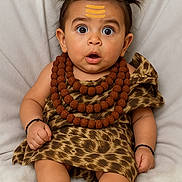 Raunit joined the competition — help win amazing prizes! baby, child, surprised, leopard_print, necklaces, beads, pigtails, hair_style, bracelets, sitting, barefoot, cute, portrait, indoors, soft_background, expression, infant, clothing, person, face