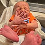 baby, infant, newborn, hands, feet, orange_clothing, blanket, diaper, face, scrunched_face, indoor, laptop, table, bottle, person, candid, cute, small_hands, small_feet, expression