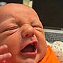 Thomas is registered to the contest to win money with this photo: baby, newborn, face, mouth, expression, skin, hand, orange_clothing, infant, closeup, person, human, cheeks, nose, head, mouth_open, eyes_closed, baby_clothing, newborn_baby, indoor