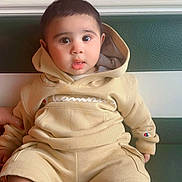 Azan joined the competition — help win amazing prizes! baby, child, hoodie, shorts, sitting, indoors, bench, green, curious, cute, portrait, face, person, clothing, casual, young, expression, comfortable, patterned_wall, colorful