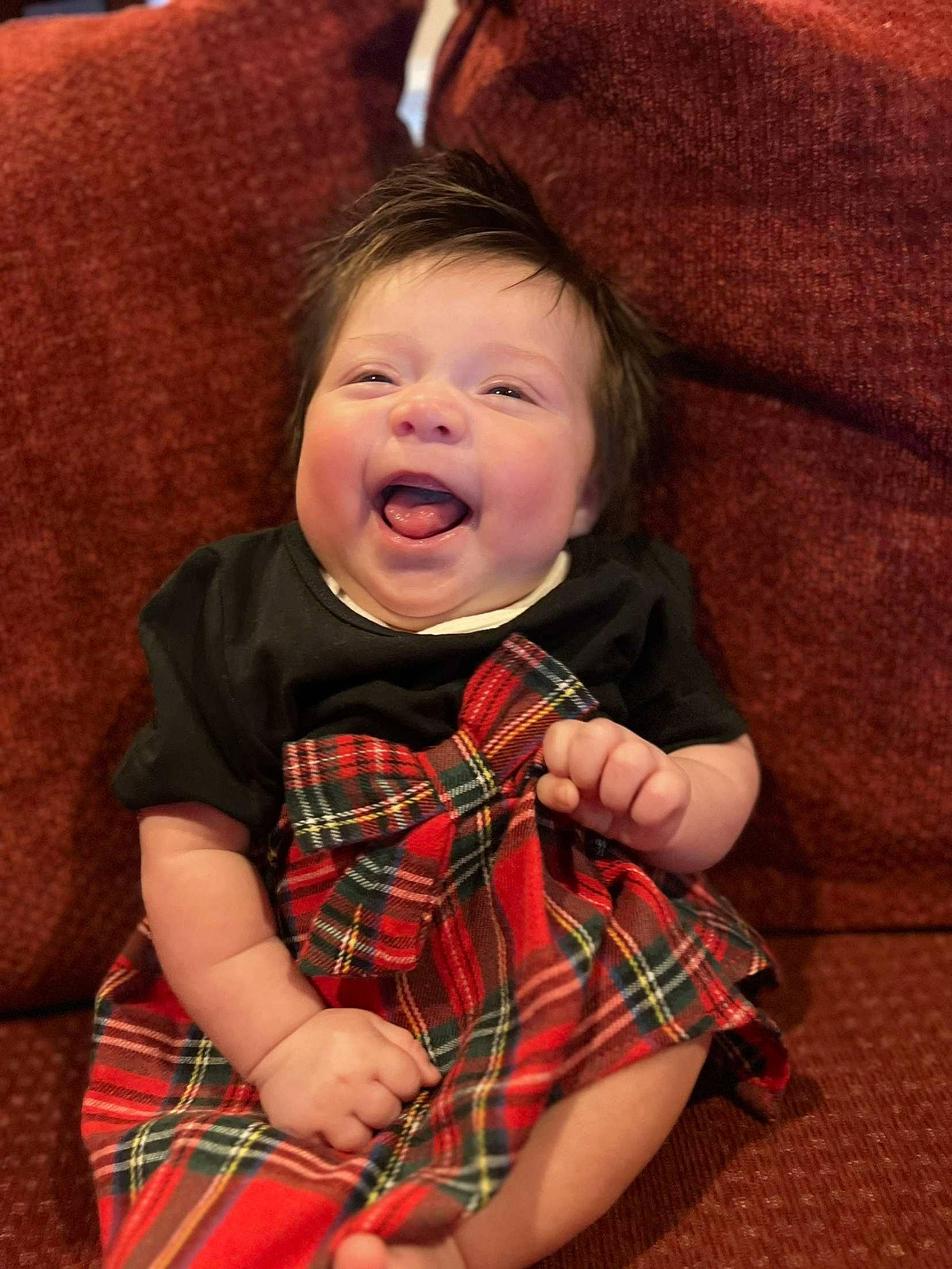 Sammy is registered to the contest to win money with this photo: baby, baby_toddler_clothing, cheek, child, collar, comfort, happy, human_body, mammal, pattern, person, plaid, red, sleeve, smile, tartan, textile, toddler, toy, tree