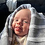 Reggie is registered to the contest to win money with this photo: baby, infant, tongue_out, blanket, knit, cozy, smile, face, hand, clothing, indoor, cute, playful, young_child, portrait, person, expression, happy, skin, warm_light