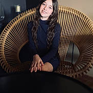 Zoé participe au concours pour gagner de l'argent avec cette photo : child, girl, smile, long_hair, wavy_hair, sitting, chair, wicker, hands, portrait, indoor, fashion, black_dress, young, person, casual, relaxed, happy, furniture, home