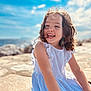 Charlie a rejoint le concours — aidez-le/la à gagner de superbes lots ! casual, child, clouds, curly_hair, cute, daytime, girl, happy, joyful, nature, outdoor, playful, portrait, sea, sky, smiling, stone, sunlight, white_dress, wind
