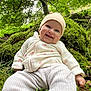 baby, smiling, forest, moss, greenery, hat, outdoor, nature, child, trees, grass, leaves, happy, cute, infant, clothing, sitting, person, daylight, scenery