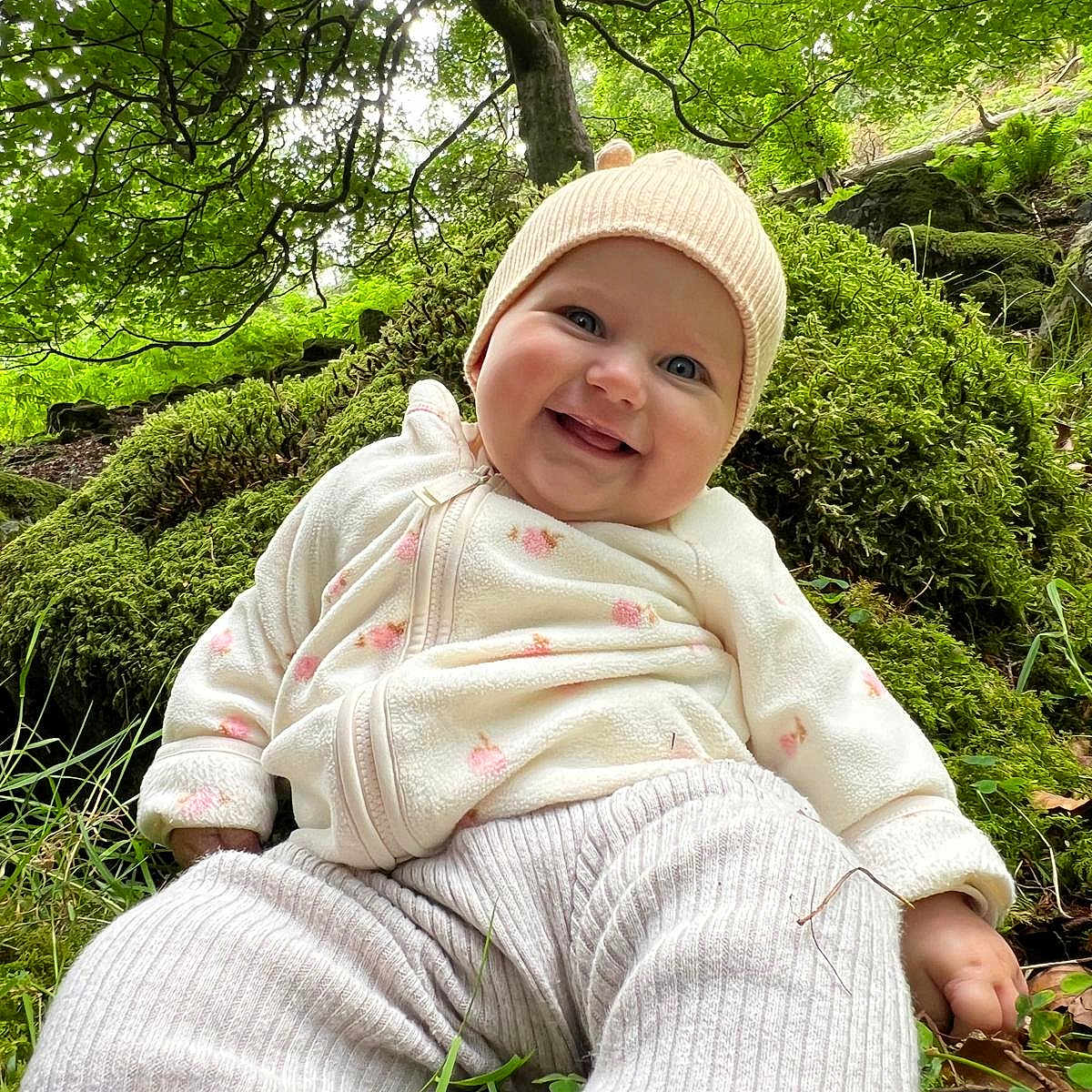 Ellise is registered to the contest to win money with this photo: baby, child, clothing, cute, daylight, forest, grass, greenery, happy, hat, infant, leaves, moss, nature, outdoor, person, scenery, sitting, smiling, trees