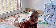 Hanaé participe au concours pour gagner de l'argent avec cette photo : baby, child, smiling, play_mat, floor, window, natural_light, indoors, colorful, cartoon_characters, long_sleeve_shirt, diaper, crawling, happy, face, person, toy_box, puzzle_mat, home, young_child