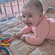 Hanaé a rejoint le concours — aidez-le/la à gagner de superbes lots ! baby, smiling, infant, blanket, toy, crib, indoor, child, pink_sweater, happy, face, hand, furniture, quilted, window, soft_toy, colorful, playing, cute, cozy