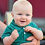 baby, child, smiling, blue_eyes, green_shirt, hand, adult_hand, happy, cute, infant, portrait, person, skin, fingers, holding, outdoor, face, short_hair, casual_clothing, close_up