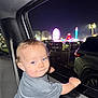 toddler, child, car, night, carnival, ferris_wheel, lights, window, seatbelt, gray_shirt, blue_eyes, curly_hair, smile, hand, vehicle_interior, amusement_park, outdoor, fun, family, portrait