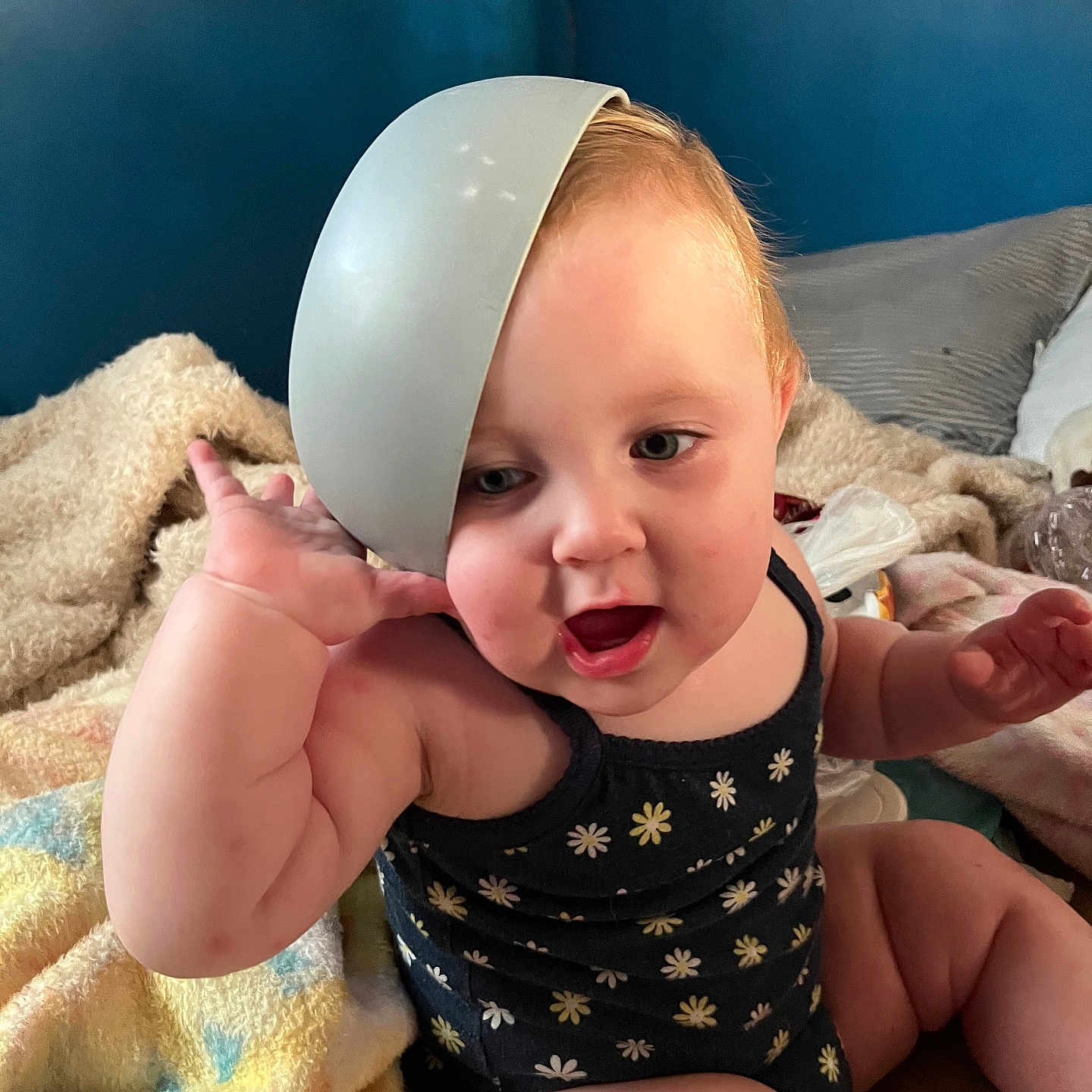 Clariece joined the competition — help win amazing prizes! baby, blanket, bowl, child, chubby, curly_hair, cute, expression, face, furniture, hand, headwear, indoor, mouth_open, onesie, person, pillow, playful, sitting, skin