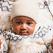 Nael participe au concours pour gagner de l'argent avec cette photo : baby, child, infant, person, face, hat, sweater, hands, winter_clothing, warm, cute, portrait, closeup, black_baby, knitwear, holding, soft, smile, cozy, indoor