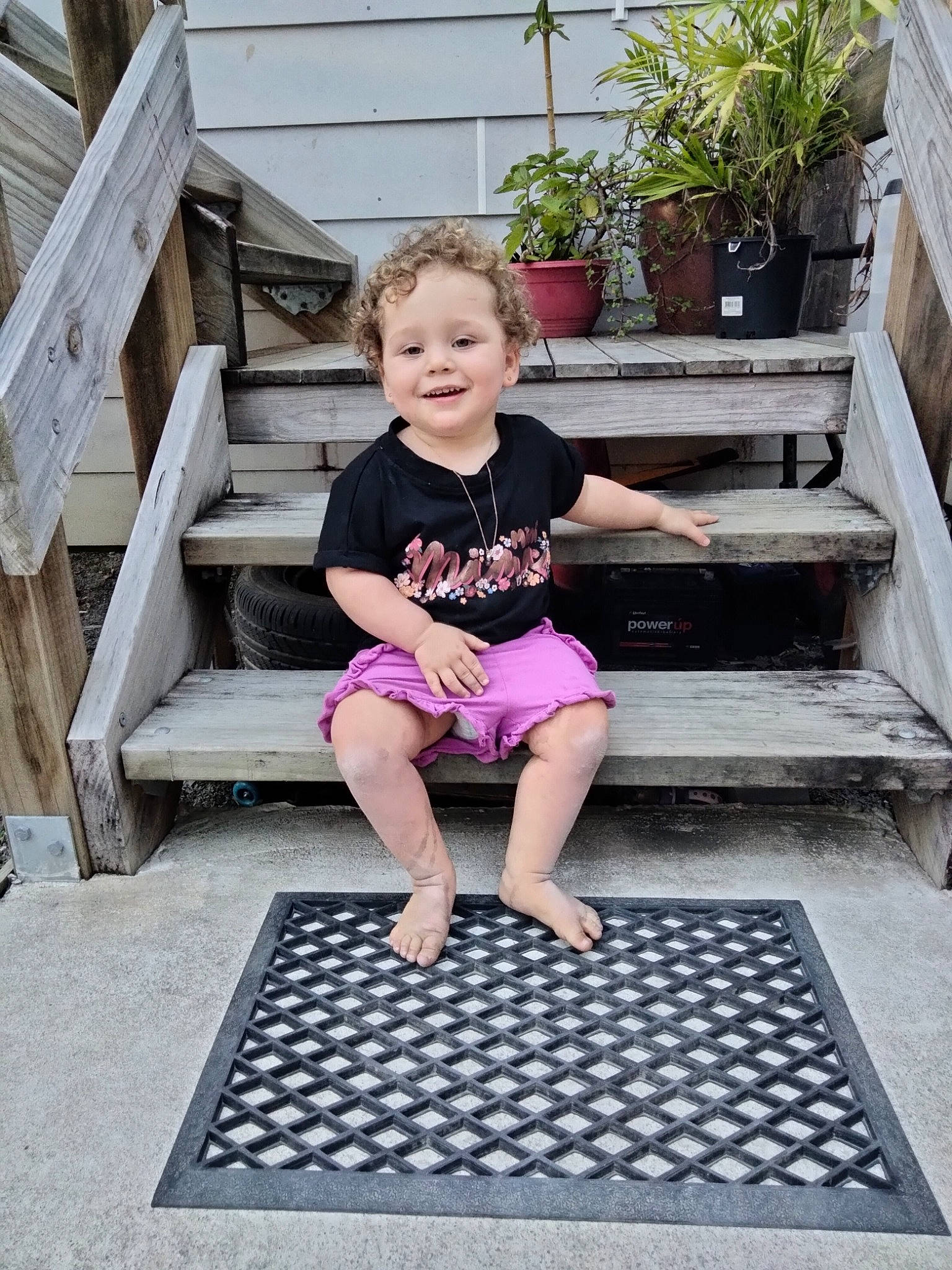 Jazmin is registered to the contest to win money with this photo: barefoot, calf, flooring, flowerpot, foot, fun, grass, houseplant, human_leg, joy, knee, leg, leisure, person, pink, plant, shorts, t_shirt, thigh, toddler