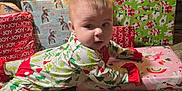 Amy joined the competition — help win amazing prizes! baby, infant, christmas_tree, ornament, presents, wrapping_paper, pajamas, carpet, holiday, festive, christmas_lights, gift, decorations, face, smile, soft_lighting, gaze, living_room, present_stack, cozy