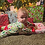 baby, infant, christmas_tree, ornament, presents, wrapping_paper, pajamas, carpet, holiday, festive, christmas_lights, gift, decorations, face, smile, soft_lighting, gaze, living_room, present_stack, cozy