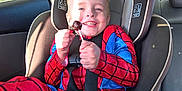 Xavier joined the competition — help win amazing prizes! child, spiderman_costume, car_seat, lollipop, smile, sunlight, car_interior, seatbelt, happy, young_child, red, blue, window, seat, fun, face, boy, daylight, candy, safety