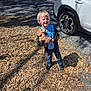 Xavier joined the competition — help win amazing prizes! child, blonde_hair, stuffed_animal, toy_dog, plastic_cup, outdoor, leaves, sunlight, cars, parking_lot, people, casual_clothing, jeans, jacket, sneakers, daytime, shadow, gravel, smiling, standing