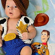 Christopher is registered to the contest to win money with this photo: baby, child, crocheted_clothing, hat, vest, blue_blanket, toy_story, woody_doll, cowboy_hat, blue_shorts, yellow_star, brown_boots, indoor, portrait, cute, infant, plush_toy, hand, face, expression