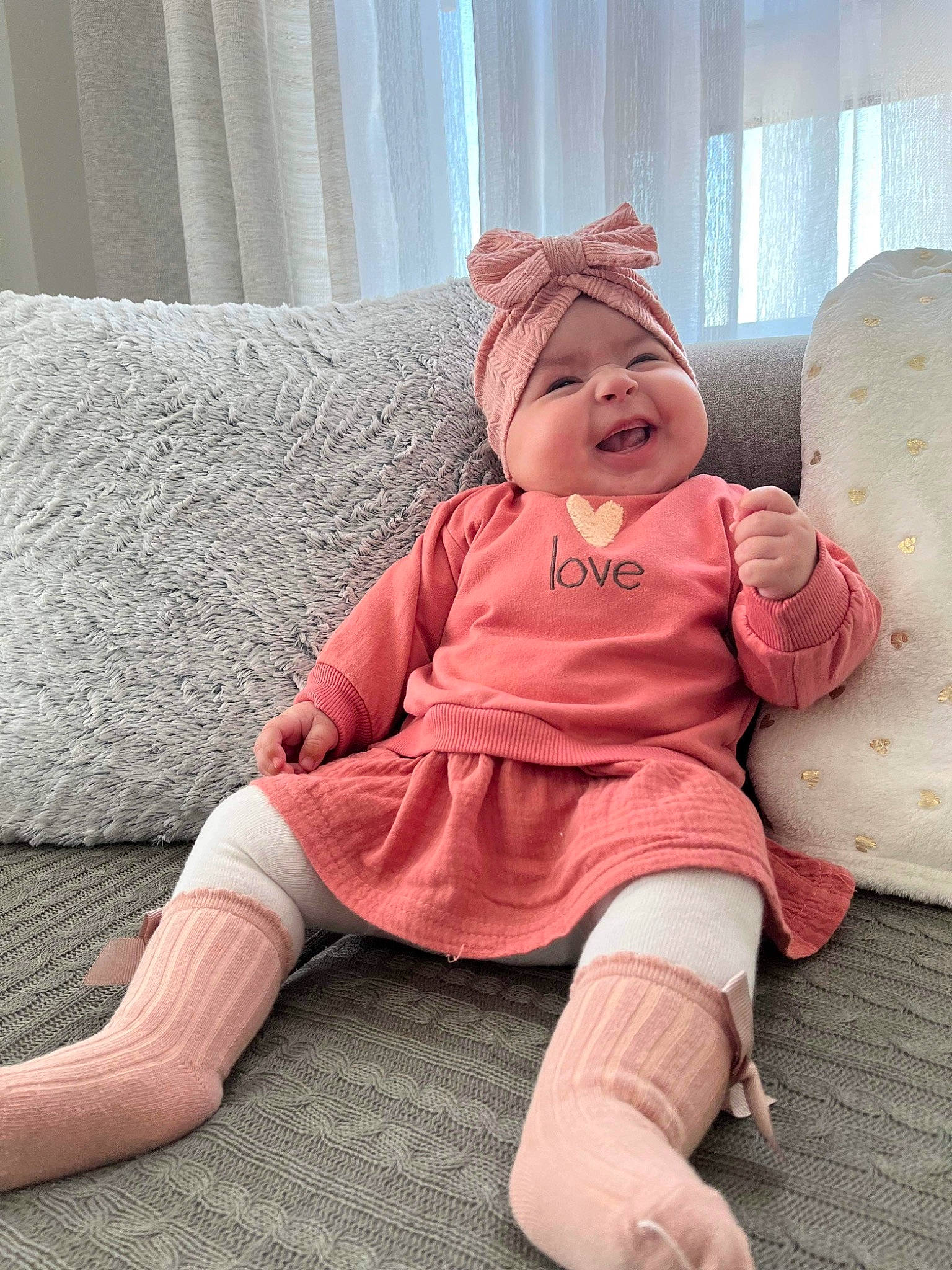 Nayla participe au concours pour gagner de l'argent avec cette photo : baby, baby_toddler_clothing, cap, carmine, child, comfort, curtain, flooring, foot, fur, happy, headwear, human_leg, knee, lap, person, pink, sitting, sleeve, smile