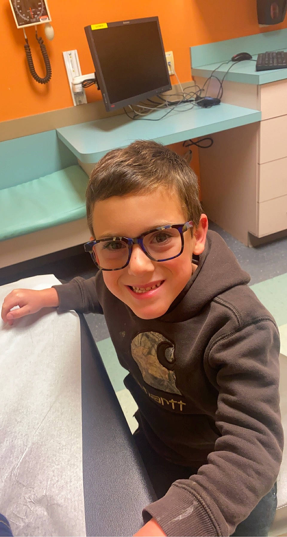 Mason is registered to the contest to win money with this photo: child, computer_keyboard, computer_monitor, desk, eyewear, flooring, fun, glasses, goggles, happy, houseplant, joy, mouth, office_supplies, peripheral, person, room, sleeve, smile, sunglasses