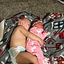 child, baby, sleeping, blanket, diaper, pink_onesie, unicorn_pattern, carpet, footwear, headband, indoor, toddler, cozy, holiday_theme, floor, resting, cute, infant, family, sibling