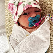 Scarlett is registered to the contest to win money with this photo: newborn, baby, pacifier, blanket, hat, floral_pattern, wrap, cushion, knitted, sleeping, infant, closeup, indoors, cozy, cute, person, child, face, resting, soft