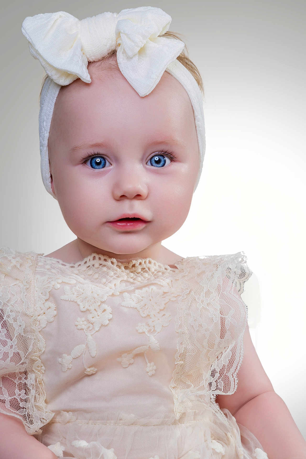 Elsie-Marie is registered to the contest to win money with this photo: baby, child, portrait, blue_eyes, headband, bow, lace_dress, close_up, innocent, soft_lighting, studio, adorable, cute, fashion, young_child, face, expression, white, delicate, infant
