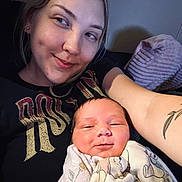 Kari is registered to the contest to win money with this photo: woman, newborn, baby, smile, tattoo, blanket, couch, indoor, portrait, closeup, happy, face, person, holding, relaxing, casual, home, comfort, young_adult, infant