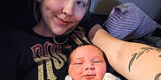Kari is registered to the contest to win money with this photo: baby, blanket, casual, closeup, comfort, couch, face, happy, holding, home, indoor, infant, newborn, person, portrait, relaxing, smile, tattoo, woman, young_adult
