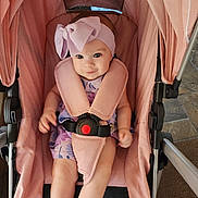 Alana joined the competition — help win amazing prizes! baby, child, stroller, pink, headband, bow, seatbelt, sitting, infant, cute, smile, indoors, clothing, person, face, legs, hands, fabric, metal, photography