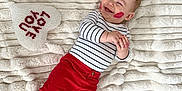 Charlie is registered to the contest to win money with this photo: baby, infant, smiling, kiss_marks, striped_shirt, red_pants, blanket, heart_pillow, xoxo_blocks, valentine_theme, cozy, plush, lying_down, bare_feet, joyful, cheeks, white_background, blanket_texture, portrait, holiday_prop