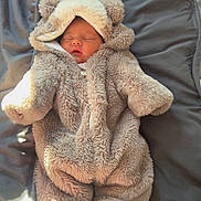 Esmae is registered to the contest to win money with this photo: baby, child, sleeping, onesie, bear_costume, fluffy, blanket, soft, cute, infant, cozy, warm, indoors, portrait, sleep, clothing, fur, adorable, resting, person