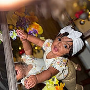 Kylie joined the competition — help win amazing prizes! toddler, child, reflection, headband, white_bow, flowers, indoor, curious, smiling, mirror, colorful, clothing, pants, shirt, hands, face, eyes, person, wood_floor, decor