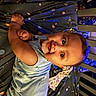 baby, infant, crib, blanket, space_theme, smile, happy, child, face, hand, clothing, blue, cute, bed, person, indoors, young, toddler, infancy, playful