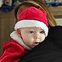 baby, child, santa_hat, red_clothing, white_fur_trim, blue_eyes, holding, embrace, indoor, portrait, holiday, festive, person, face, closeup, cute, warm, soft_light, blond_hair, expression