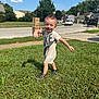 Junior is registered to the contest to win money with this photo: child, toddler, smiling, grass, outdoor, daytime, suburban, sidewalk, street, trees, blue_sky, clouds, nike, dress, sandals, playful, happy, person, greenery, sunlight