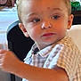 Junior is registered to the contest to win money with this photo: child, toddler, face, person, shirt, plaid, table, chair, indoor, blue_eyes, short_hair, expression, curious, sitting, food, drink, flower, can, casual, background