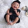 adorable, baby, black_dress, child, cute, earrings, feet, hands, happy, headband, indoor, infant, knitted_zebra, lying_down, playful, portrait, smile, soft_texture, toy, white_fur