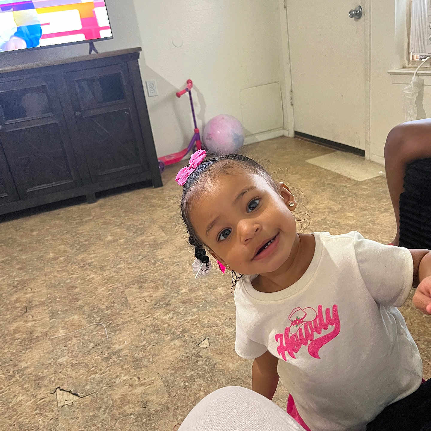 Nyarrie joined the competition — help win amazing prizes! toddler, child, smile, pink_bow, white_shirt, indoor, living_room, television, cabinet, floor, toy_scooter, ball, door, window, curtain, earrings, person, playful, happy, casual_clothing