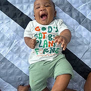 Synceir is registered to the contest to win money with this photo: baby, child, smiling, laughing, toddler, infant, clothing, shirt, shorts, socks, patterned_quilt, bedspread, happy, portrait, person, indoor, cute, joyful, playful, hands